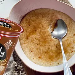 Schüssel mit Milchreis mit Zimt, daneben ein Becher "High Protein Milchreis Zimt" von Dr. Oetker.