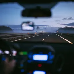 Conduite de nuit sur une autoroute italienne, respectant la limitation de vitesse. Brouillard léger, lumières des phares et du tableau de bord.