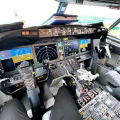 Kokpit samolotu Boeing 737 z widokiem na panele sterowania, ekrany nawigacyjne i yoke.