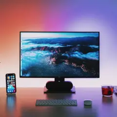 Biurko z telefonem, słuchawkami i klawiaturą. Na monitorze 144hz do 600 zł krajobraz górski.