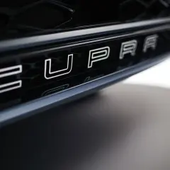 Napis CUPRA na czarnym grillu samochodu.