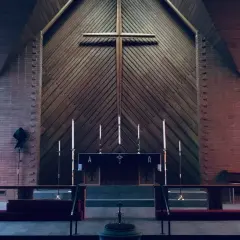 Wnętrze kościoła z ołtarzem, krzyżem i witrażami.