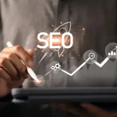Ręka z rysikiem nad tabletem, nad nim świecący napis SEO i wykres wzrostu. To symbol sprawdzania linków i optymalizacji.