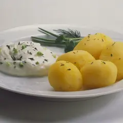 Kartoffeln mit Quark, garniert mit Schnittlauch und Dill, auf einem weißen Teller. Ein einfaches, aber köstliches Gericht.