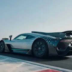 Srebrny Mercedes-AMG ONE z charakterystycznym wzorem gwiazdek na karoserii pędzi po torze wyścigowym.