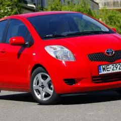 Czerwony Toyota Yaris 2009 z polskimi tablicami WE 2927N jedzie po ulicy.