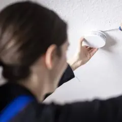 Frau tauscht Rauchmelder aus, da die Frist abgelaufen ist. Sicherheit geht vor!