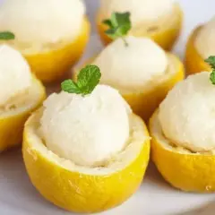 Sorbet cytrynowy w połówkach cytryn, udekorowany listkami mięty.