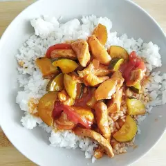 Pyszny kurczak po tajsku z cukinią i papryką, podany na ryżu. Aromatyczne danie, które zachwyci każdego smakosza.