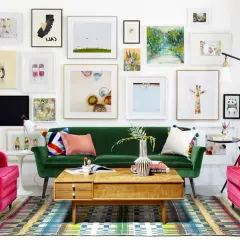 Salon w stylu new eklektyzm: zielona sofa, fuksjowe fotele, kolorowy dywan i ściana pełna różnorodnych obrazów.