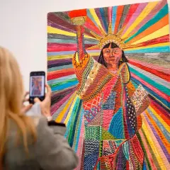 A woman photographs a vibrant quilt depicting the Statue of Liberty, a powerful piece by Asian American artists celebrating diversity.