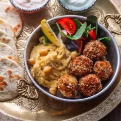 Pyszne jedzenie koszerne: hummus, falafel, świeże pieczywo i sałatka na ozdobnej tacy.