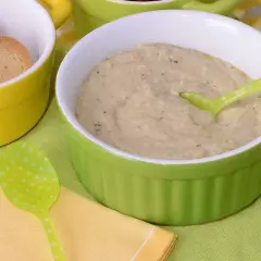 Un cremoso puré de berenjena servido en un cuenco verde, acompañado de galletas tostadas en un cuenco amarillo.