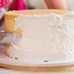 Nakładanie puszystego tynku Milky Way na tort. Kremowa masa pokrywa boki ciasta, tworząc apetyczny wygląd.