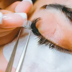 Precyzyjne przedłużanie rzęs 2-3d. Stylistka z perfekcyjnym manicurem dokłada kolejne kępki, tworząc efekt wow.