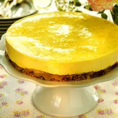 En härlig citronmousse till tårta, med en krispig botten och glansig topping, serveras på ett vackert tårtfat.
