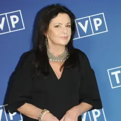 Zofia Czernicka w czarnej kreacji, z okazałą biżuterią, na tle logo TVP. Wiele osób zastanawia się, kim są jej partnerzy.