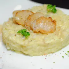 Un crémeux risotto poire gorgonzola, garni de Saint-Jacques poêlées et d'une touche de persil frais.