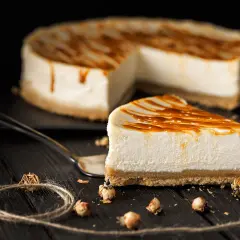 Una fetta di cheesecake fredda senza gelatina, con glassa al caramello, su un piatto scuro.