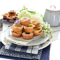 Montón de pastel de nata portugal, espolvoreados con azúcar glas, decorados con flores y servidos en platos de cerámica.