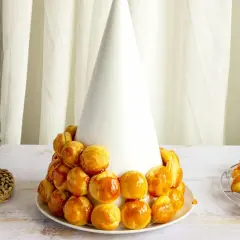 Tarta de profiteroles en proceso, con los pastelitos dorados y brillantes, listos para ser cubiertos de caramelo.