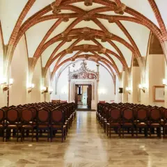 Wnętrze sali z rzędami krzeseł i ozdobnym sklepieniem.