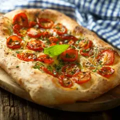 Pyszna focaccia z pomidorkami koktajlowymi i bazylią. Idealna jako przekąska, dodatek do sałatek lub jako samodzielne danie. Z czym jeść focaccię? Z tym, co lubisz!