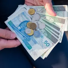 Dłonie trzymają polskie banknoty i monety. Czy mam 60 lat i 10 lat pracy, czy dostanę emeryturę?