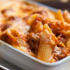 Un invitante piatto di pasta al forno, con penne ricoperte da un ricco sugo e formaggio fuso dorato.