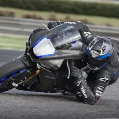 Piloto en Yamaha R1, la moto más potente, inclinado en una curva en circuito.