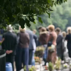 Ludzie na cmentarzu, w zadumie. Czy można pochować zmarłego w innym mieście? Pytanie, które zadaje sobie wielu.