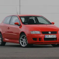 Czerwony Fiat Stilo 1.9 JTD na tle białej ściany, gotowy do jazdy.