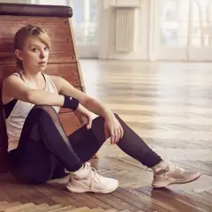 Młoda kobieta w stroju sportowym siedzi na podłodze, szukając motywacji do ćwiczeń.