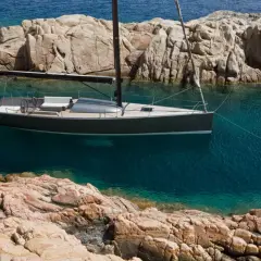 Un elegante yacht Brenta naviga in acque cristalline, ormeggiato tra scogliere rocciose.