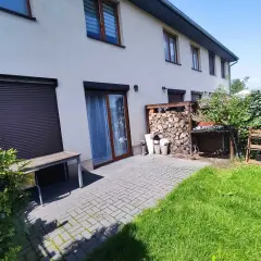 Taras przy domu w Rudzie Śląskiej, z drewnianą ławką, stertą drewna i zielonym ogrodem.