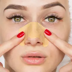 Kobieta z ręcznikiem na głowie stosuje plaster na nos, by pozbyć się głębokich wągrów.