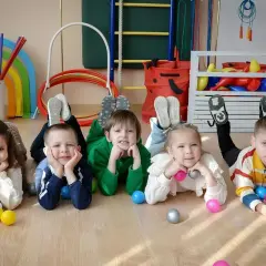 Dzieci leżą na podłodze w żłobku, bawiąc się piłeczkami. To pokazuje, ile trwa adaptacja w żłobku.