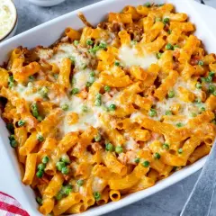 Herzhaftes Rigatoni al Forno mit Erbsen und geschmolzenem Käse in einer Auflaufform, bereit zum Servieren.