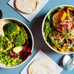 Gesundes Essen nach dem Joggen: Zwei bunte Bowls mit Hummus, Brokkoli, Edamame, Rote Bete, Süßkartoffel, Linsen und Granatapfelkernen.