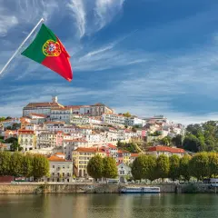 Flaga Portugalii nad rzeką. Miasto na wzgórzu, idealne na wakacje, gdzie portugalia temperatura wody zachęca do kąpieli.
