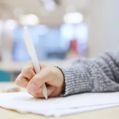 Dłoń pisze długopisem na kartce. Czy to próba przed maturą z angielskiego i ile słów na maturze z angielskiego?