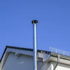Edler Edelstahl-Schornstein mit 150 mm Durchmesser für einen Pelletofen, ragt vor blauem Himmel empor.