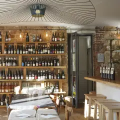 Ambiance chaleureuse dans la cave à manger, avec des étagères remplies de bouteilles de vin, des tables dressées et un bar en bois.