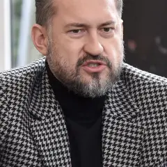 Marcin Prokop w czarnej golfie i marynarce w pepitkę.