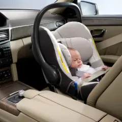 Un bébé dort paisiblement dans un siège auto, prêt pour le voyage. La **taille pour monter devant en voiture** est parfaite pour ce siège.