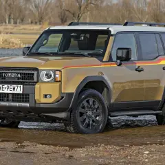 Złoty Toyota Land Cruiser wjeżdża do wody, gotowy na przygodę.