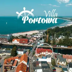 Widok z lotu ptaka na port i plażę w Darłówku. W centrum widoczny budynek z czerwonym dachem, otoczony kołem.