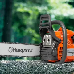 Pomarańczowa piła łańcuchowa Husqvarna 445 na pniu drzewa. Sprawdź husqvarna 445 dane techniczne, by poznać jej możliwości.