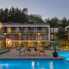 Relaks przy basenie w Saltic Resort & Spa. Nowoczesne budynki, leżaki i palmy tworzą idealne miejsce na wypoczynek.