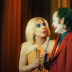 Joker e Harley Quinn, con microfoni in mano, si guardano intensamente. La trama del film si infittisce.